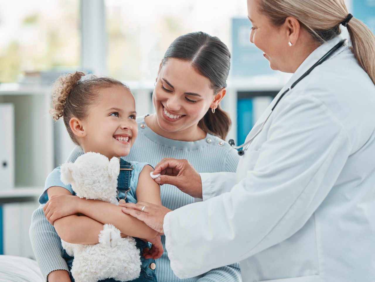 Ein Arzt benutzt einen Wattebausch auf dem Arm eines kleinen Mädchens, während er sie impft