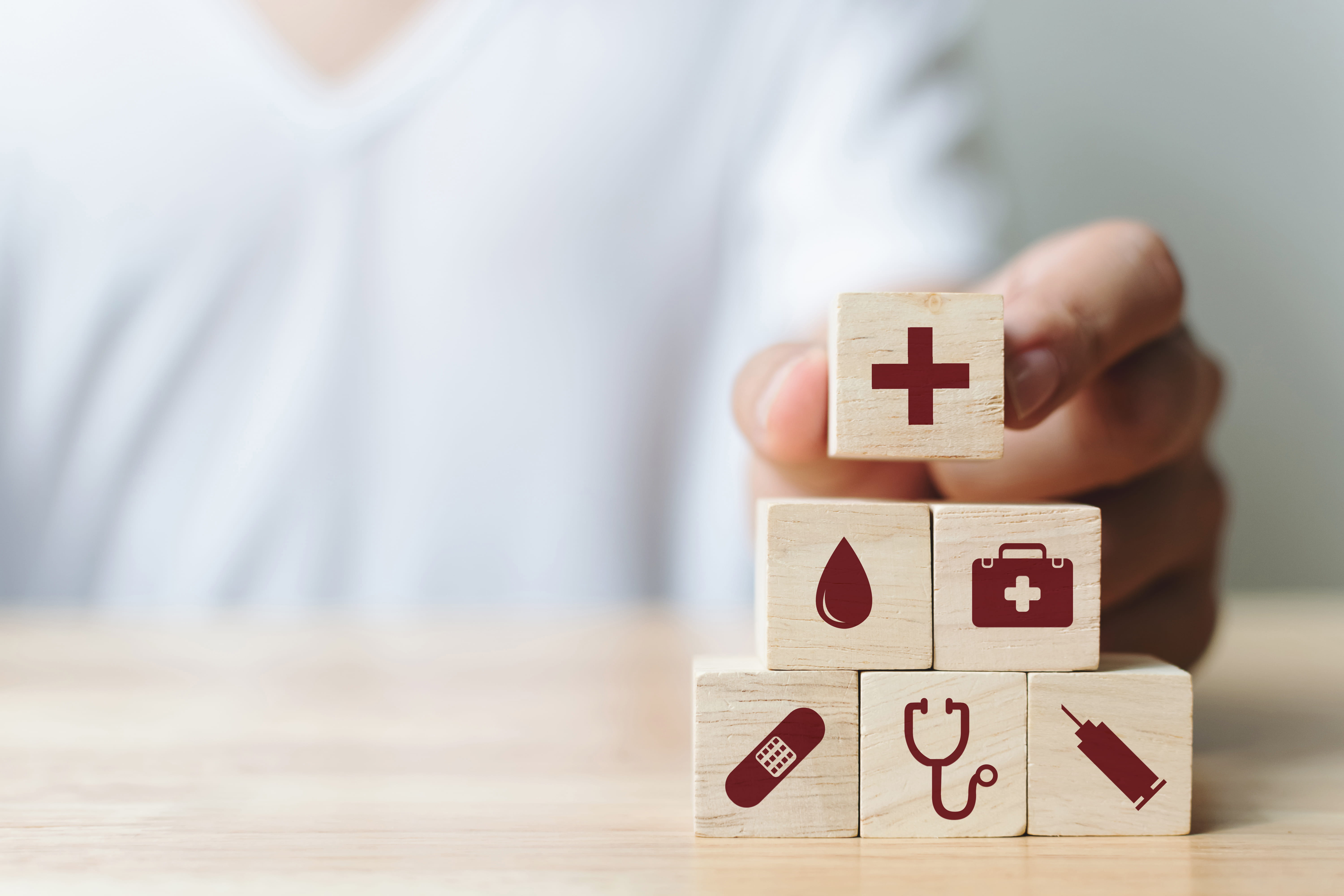 Dominosteine mit medizinischen Icons werden von einer Hand aufeinandergelegt