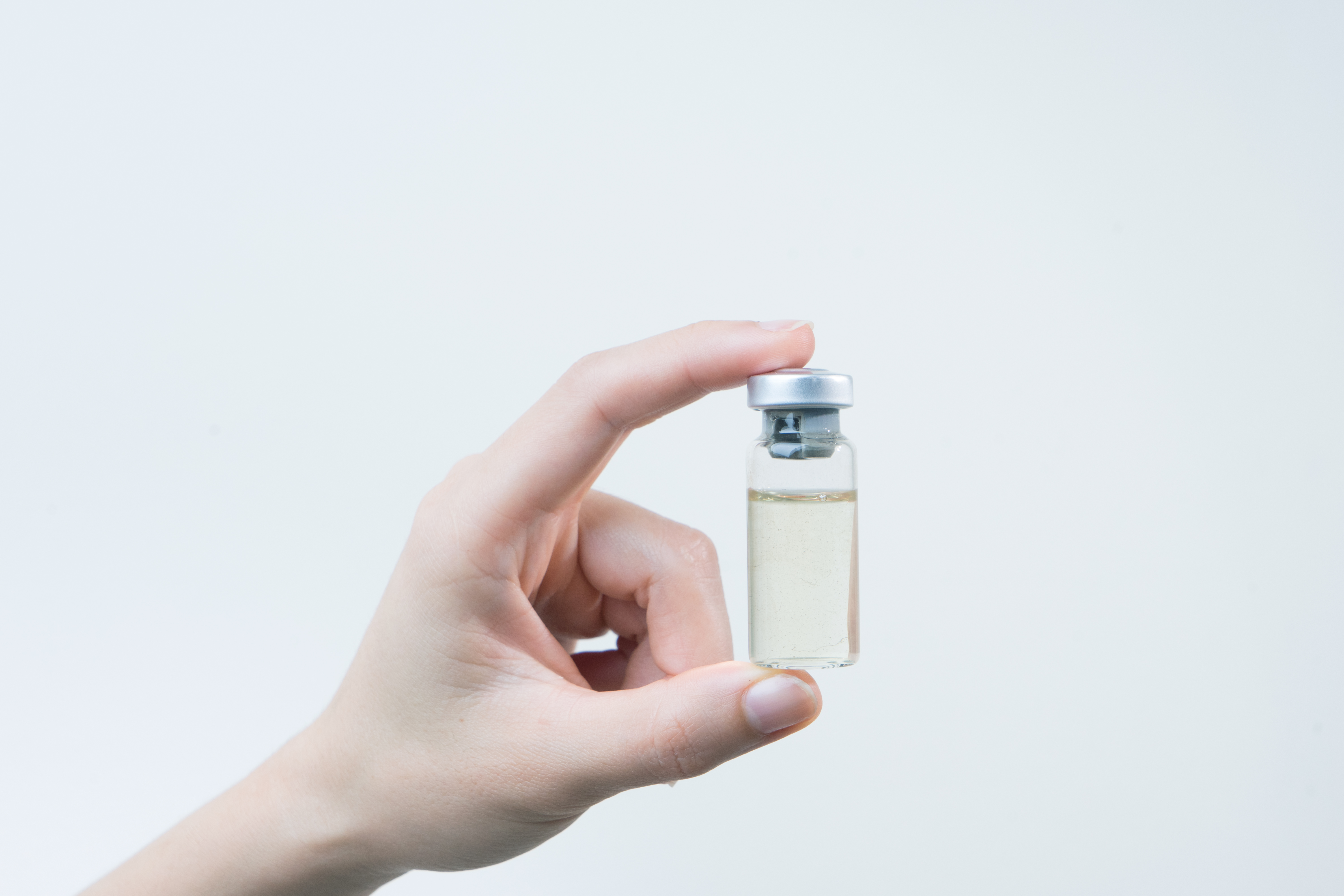 Hand hält kleines Impffläschchen in der Hand