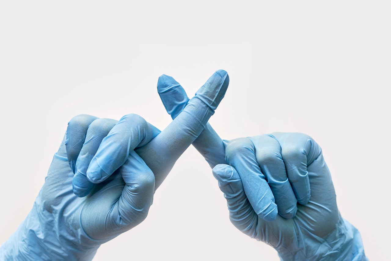 Hände mit Handschuhen machen mit den Fingern ein Kreuz