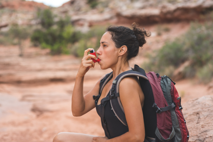 Frau ist wandern und nutzt ein Asthmaspray