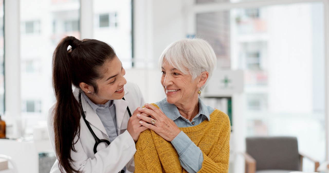 Junge Ärztin umarmt ältere Patientin